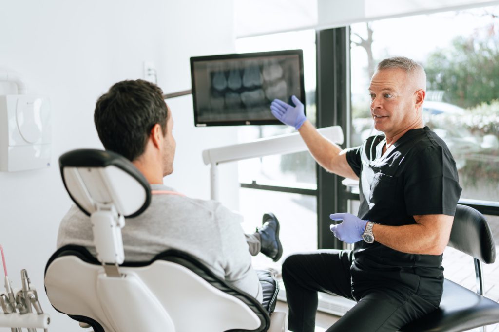 dental-implants-and-imaging-consultation A Dental Xray is shown to a patient while consulting about Dental Implants in Victoria